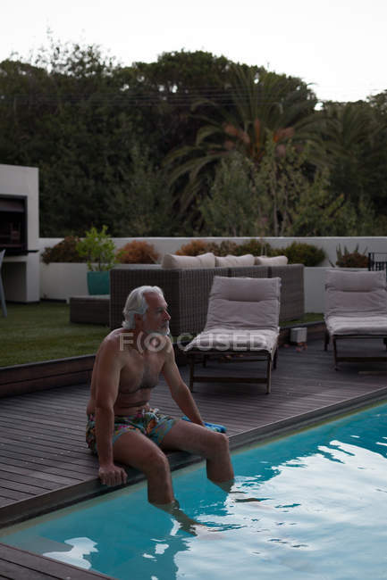 Активних старшим людини, що сидить на краю басейну — стокове фото