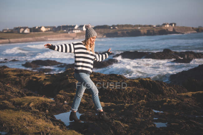 Femme marchant avec les bras tendus à la plage par une journée ensoleillée — Photo de stock
