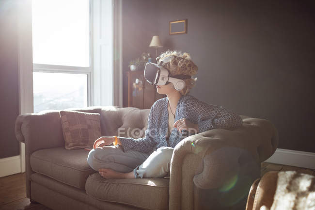 Жінка використовує гарнітуру віртуальної реальності у вітальні вдома — стокове фото