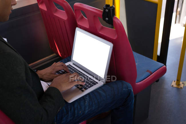Milieu de la section de l'homme d'affaires en utilisant un ordinateur portable tout en voyageant en bus — Photo de stock