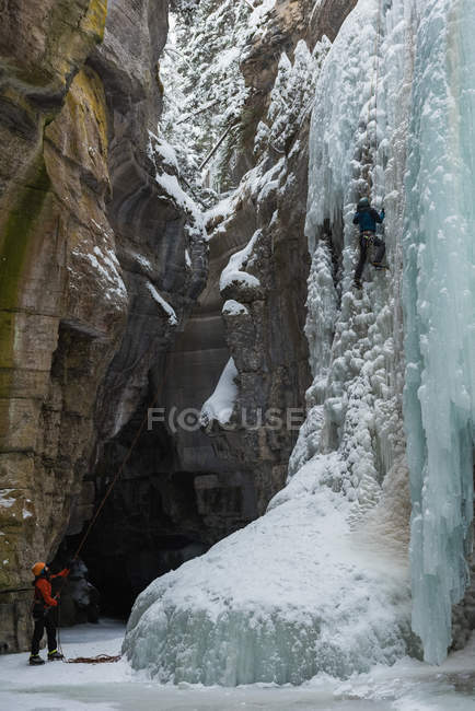 Homme grimpeur escalade montagne de glace pendant l'hiver — Photo de stock