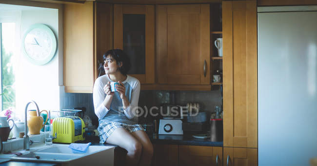 Mulher atenciosa tomando café na cozinha em casa — Fotografia de Stock