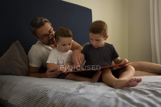 Батька і сини, дивлячись на Сімейний фотоальбом у спальні будинку — стокове фото