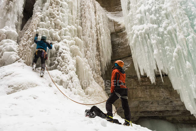 Masculino alpinista escalando montanha de gelo durante o inverno — Fotografia de Stock