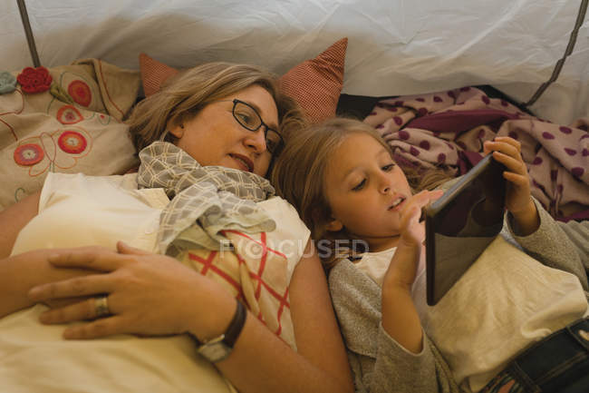 Mãe e filha usando tablet digital na barraca em casa — Fotografia de Stock