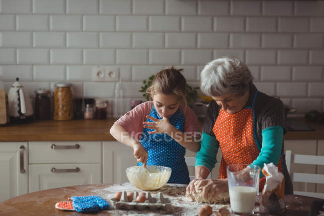 Grand-mère et petite-fille préparant des biscuits dans la cuisine à la maison — Photo de stock
