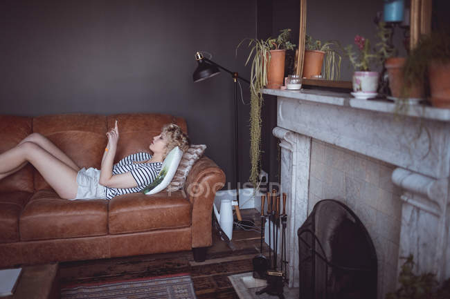 Donna che utilizza il telefono cellulare in soggiorno a casa — Foto stock