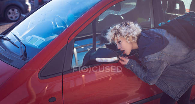 Молодая женщина смотрит на зеркало заднего вида автомобиля — стоковое фото