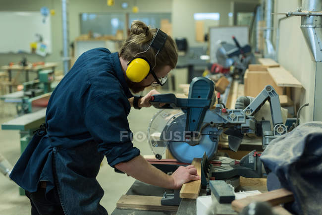 Мужской плотник с помощью станка для резки шлифовального станка в мастерской — стоковое фото