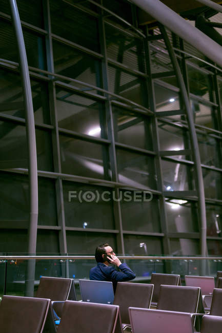 Бізнесмен розмовляє по мобільному телефону в зоні очікування в аеропорту — стокове фото