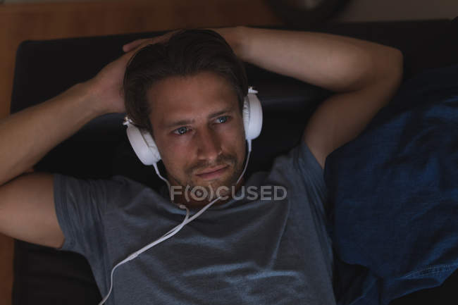 Чоловік слухає музику на навушниках у вітальні вдома — стокове фото