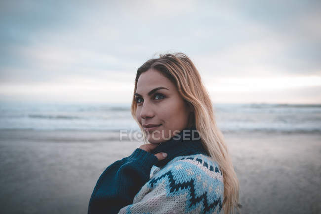 Donna riflessiva in piedi su una spiaggia al crepuscolo — Foto stock