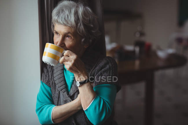 Mulher idosa atenciosa tomando café em casa — Fotografia de Stock