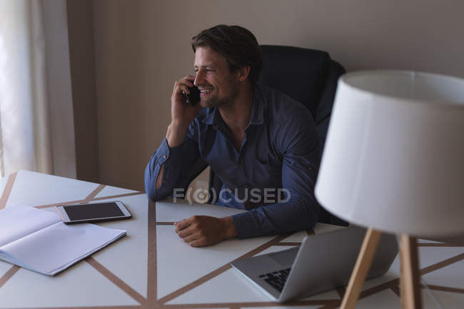 Happy man talking on mobile phone at home — Stock Photo