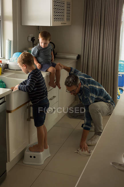 Отец с сыном убирают кухню дома — стоковое фото