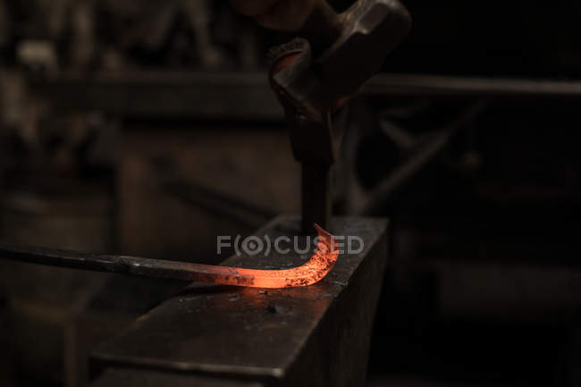 Blacksmith hammering a hot metal rod — Stock Photo
