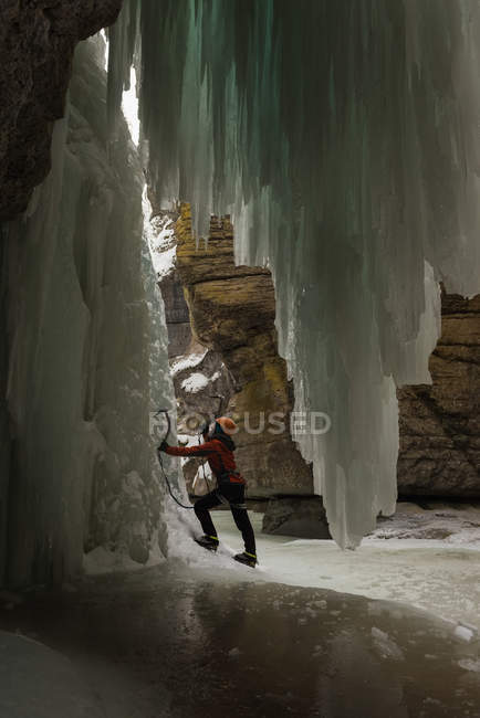 Female rock climber climbing rocky ice mountain during winter — Stock Photo