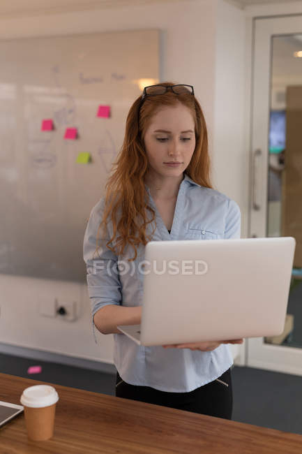 Young female executive using laptop in office — Stock Photo