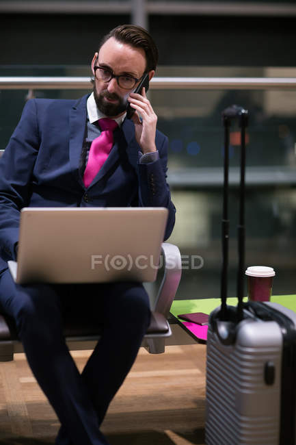 Бизнесмен разговаривает по мобильному телефону в зале ожидания аэропорта — стоковое фото
