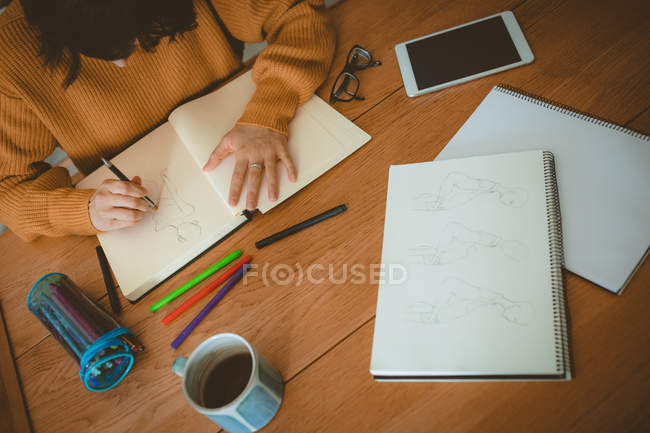 Woman drawing a sketch in a book at home — Stock Photo