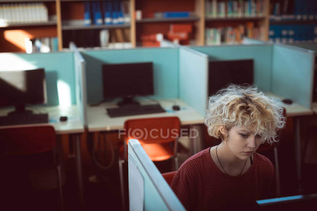 Молода жінка працює на комп'ютері в бібліотеці — стокове фото