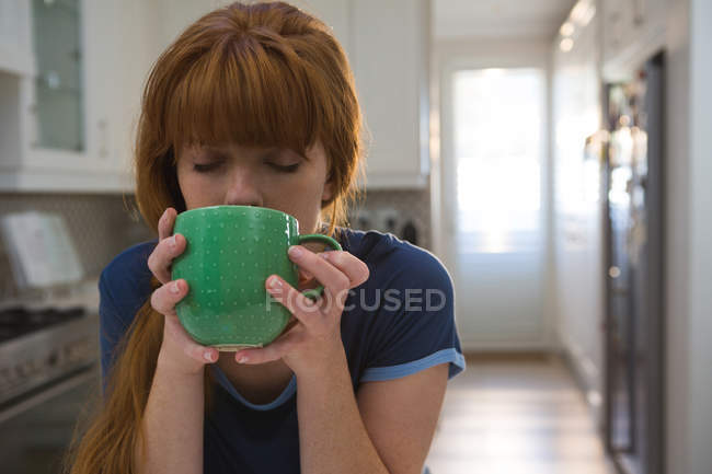 Frau trinkt Kaffee im grünen Becher zu Hause — Stockfoto