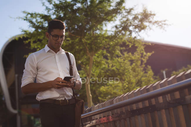 Бізнесмен, використовуючи мобільний телефон на вулиці в сонячний день — стокове фото