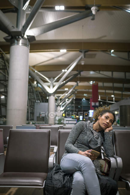 Женщина, использующая мобильный телефон в зоне ожидания аэропорта — стоковое фото