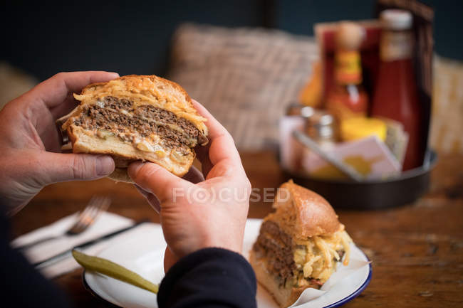 Primer plano del hombre comiendo hamburguesa en el restaurante - foto de stock