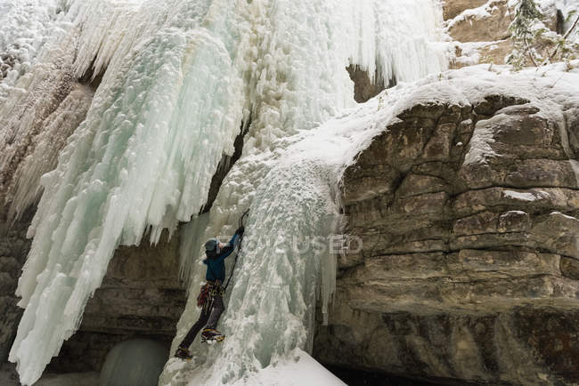 Hombre escalador escalada montaña de hielo durante el invierno - foto de stock