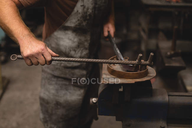 Ferreiro moldando uma haste de metal na oficina — Fotografia de Stock