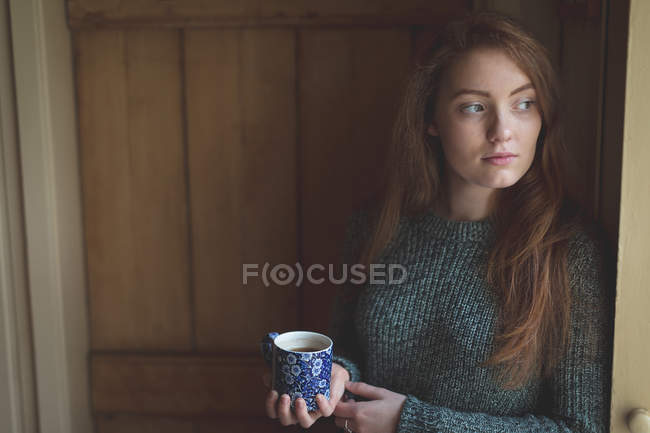 Mujer pensativa tomando té verde en casa - foto de stock