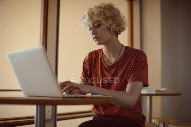 Mulher usando laptop na cafetaria na universidade — Fotografia de Stock