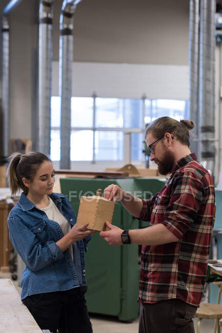 Мужские и женские плотники осматривают деревянную мебель в мастерской — стоковое фото