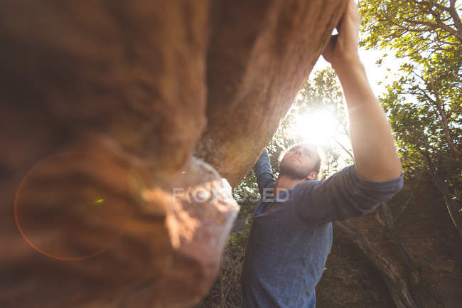 Caminhante masculino escalando montanha rochosa no campo em um dia ensolarado — Fotografia de Stock