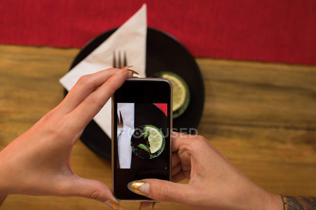 Mujer haciendo clic en la foto del desayuno con teléfono móvil en el restaurante - foto de stock