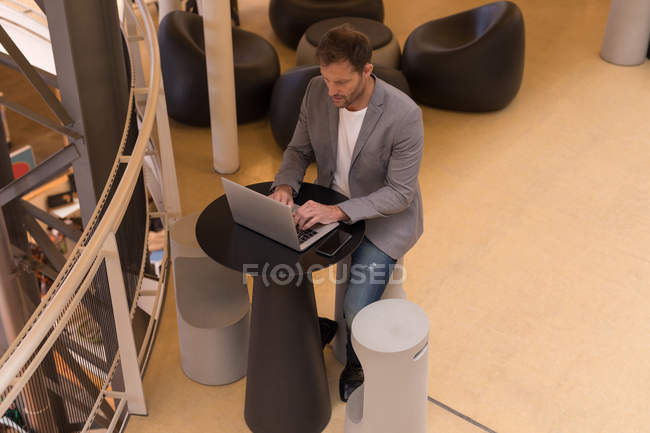 Hombre de negocios atento usando el ordenador portátil en la oficina - foto de stock