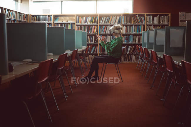 Young woman using virtual reality headset in library — Stock Photo