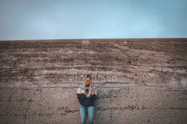 Junge Frau benutzt Handy am Strand — Stockfoto