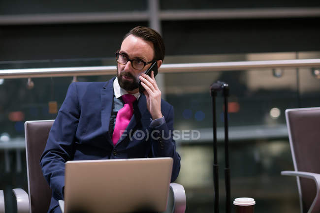Бизнесмен разговаривает по мобильному телефону в зале ожидания аэропорта — стоковое фото