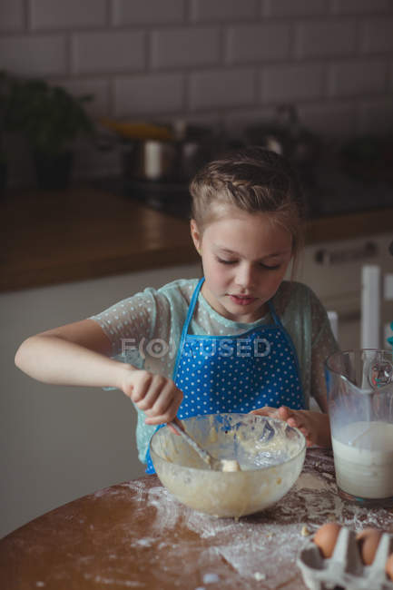Маленькая девочка готовит печенье на кухне дома — стоковое фото