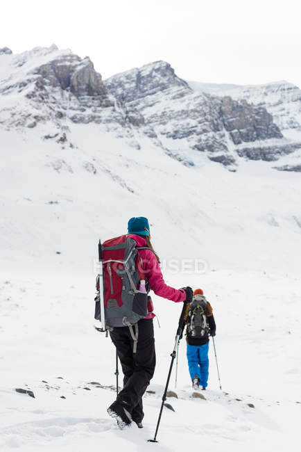 Rückansicht eines Paares, das im Winter auf einem schneebedeckten Berg spaziert — Stockfoto