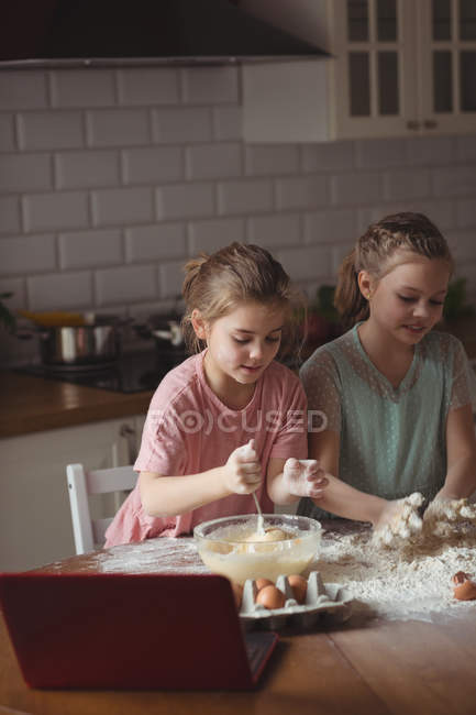 Hermanos preparando magdalena en la cocina en casa - foto de stock
