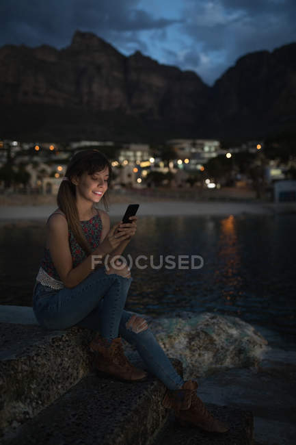 Mujer joven usando el teléfono móvil en la piscina de roca - foto de stock