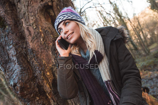 Молодая женщина разговаривает по мобильному телефону в лесу — стоковое фото