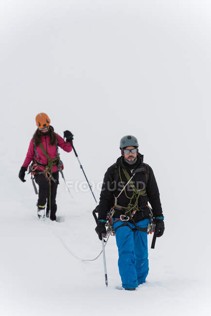 Coppia che cammina con imbracatura su una montagna innevata durante l'inverno — Foto stock