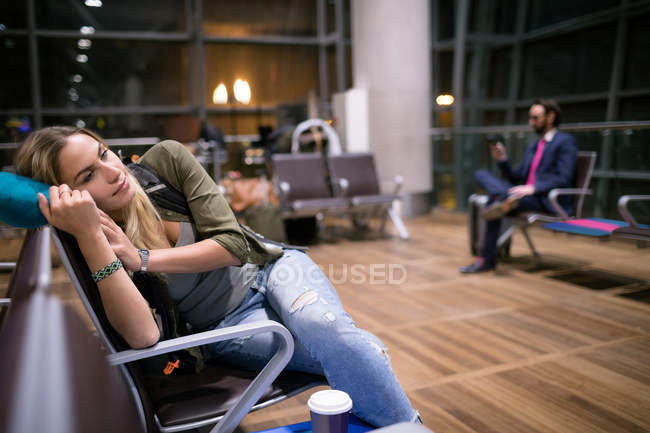 Mujer relajándose en la zona de espera en la terminal del aeropuerto - foto de stock
