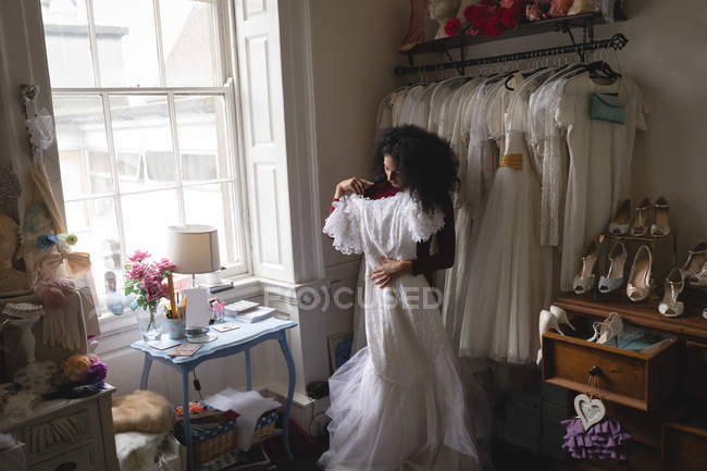 African woman selecting wedding dress from clothes hangers at boutique — Stock Photo