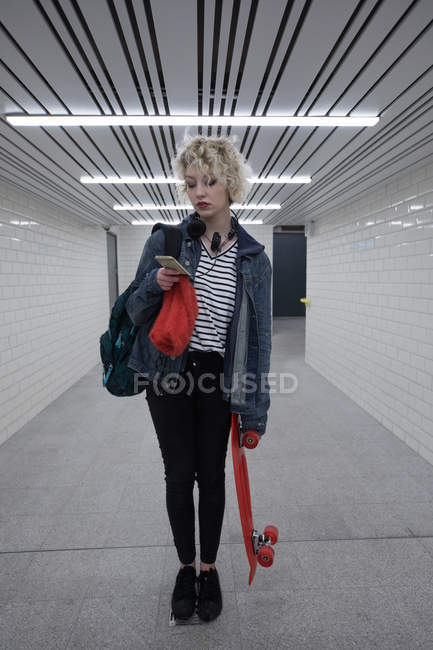 Young woman using mobile phone in subway — Stock Photo