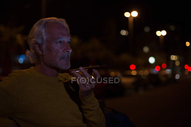 Senior man talking on mobile phone in city at night — Stock Photo